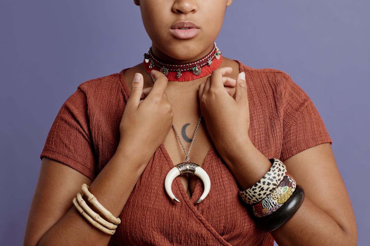 Fashionable woman showcasing unique jewelry, bracelets, and a moon choker necklace against a purple background.